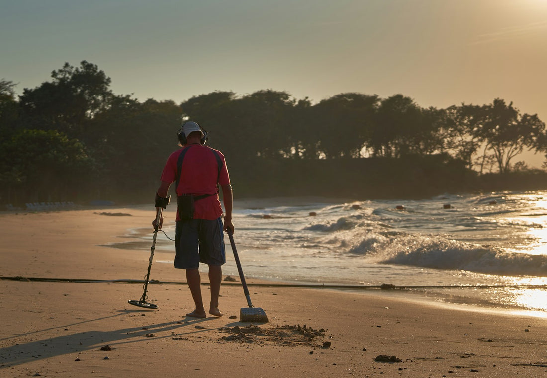 Prospection au détecteur de métaux sur une plage au coucher du soleil